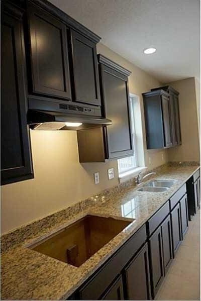 kitchen featuring a sink, light stone counters, under cabinet range hood, and black electric cooktop