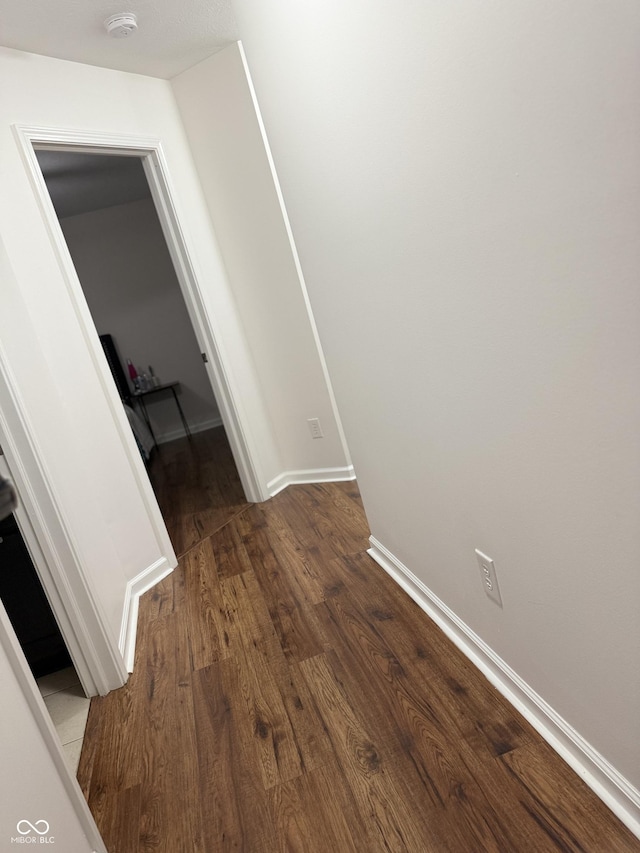corridor featuring baseboards and wood finished floors