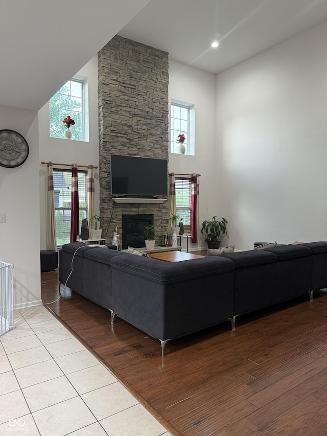 living room with a high ceiling, a fireplace, and light wood-type flooring