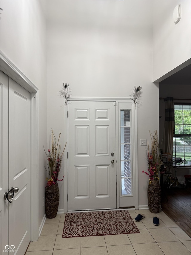 entryway featuring baseboards, a high ceiling, and light tile patterned floors