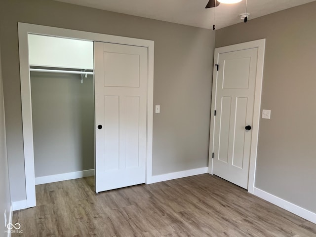 unfurnished bedroom featuring baseboards, a closet, and wood finished floors