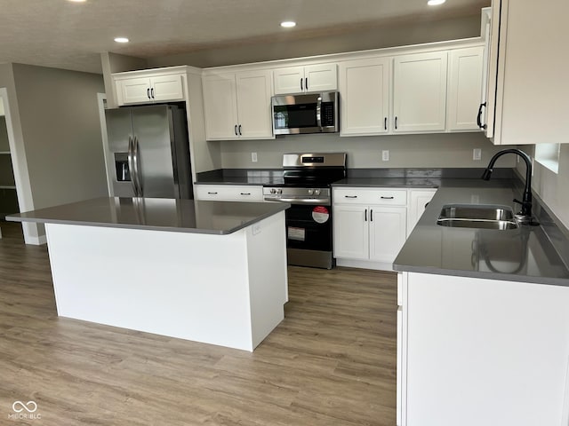kitchen featuring stainless steel appliances, dark countertops, recessed lighting, and a sink