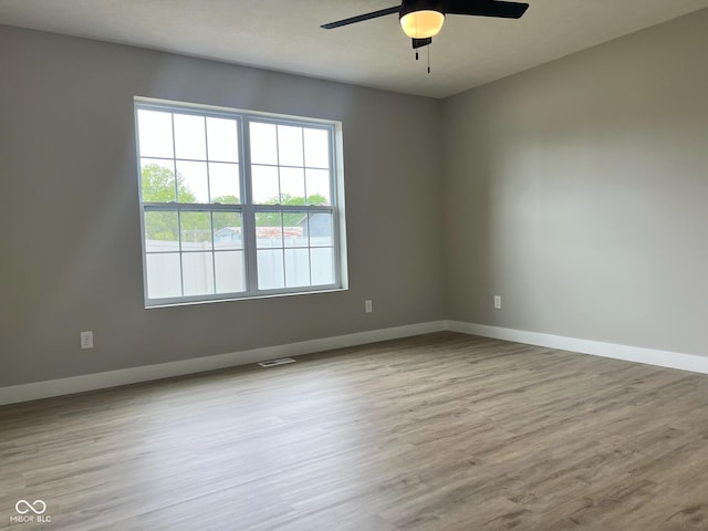 empty room with baseboards, ceiling fan, and wood finished floors