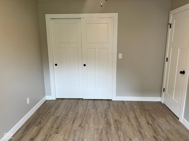 unfurnished bedroom with baseboards, wood finished floors, and a closet