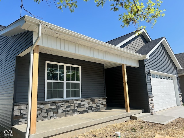 view of front of home featuring a garage, covered porch, stone siding, and a shingled roof