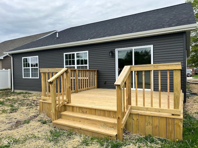rear view of property with a wooden deck and roof with shingles