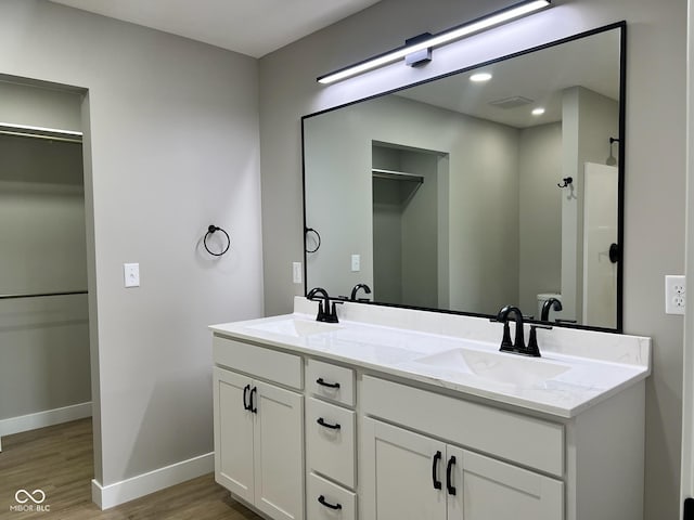 bathroom featuring double vanity, baseboards, a sink, and wood finished floors