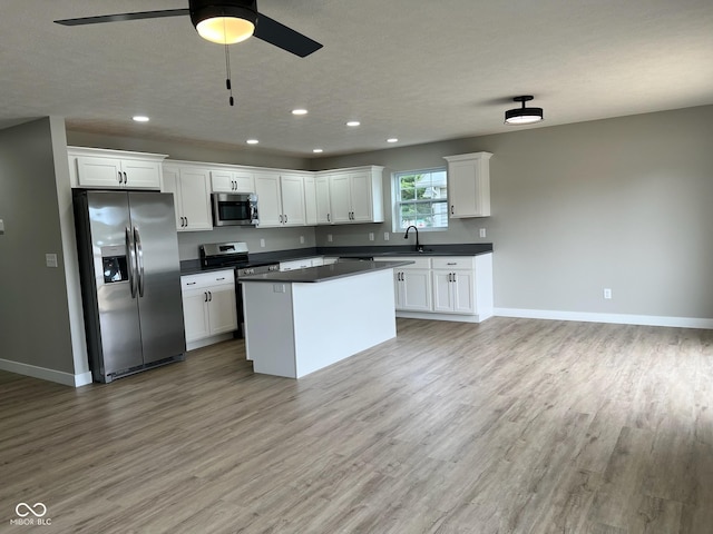 kitchen featuring dark countertops, light wood-style floors, stainless steel appliances, recessed lighting, and a ceiling fan