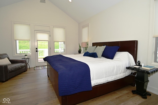 bedroom featuring access to outside, wood finished floors, and lofted ceiling