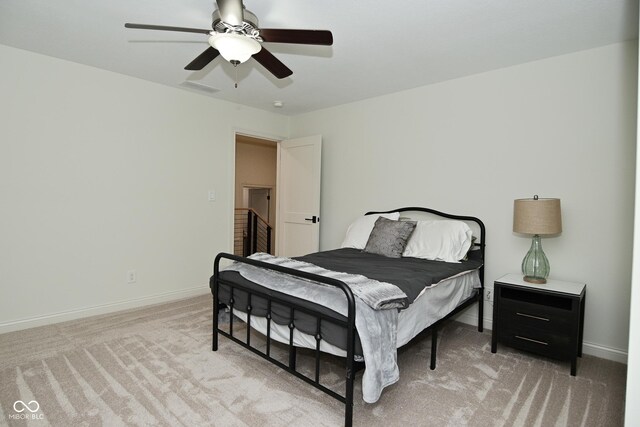 bedroom featuring light colored carpet, visible vents, baseboards, and ceiling fan