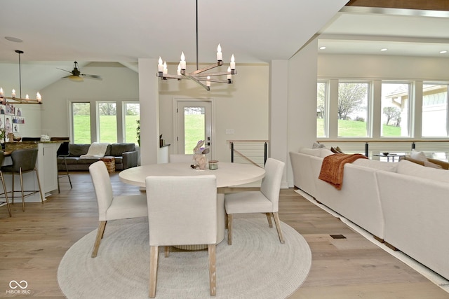 dining room with light wood finished floors, vaulted ceiling, ceiling fan with notable chandelier, and recessed lighting