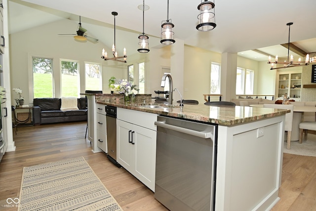 kitchen with an island with sink, a sink, open floor plan, light stone countertops, and dishwasher
