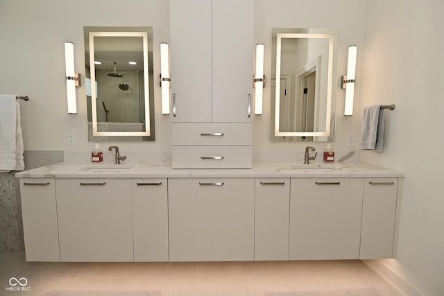 full bath featuring a sink, double vanity, and tiled shower