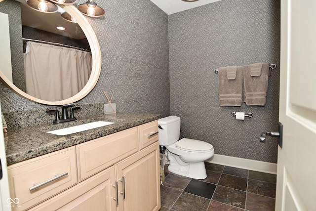 bathroom with toilet, vanity, and stone finish flooring