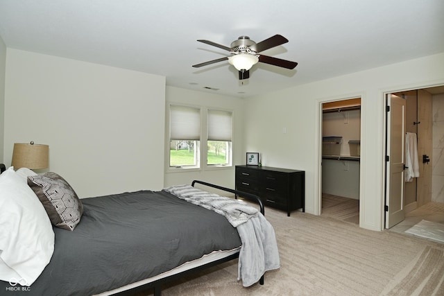 bedroom featuring a closet, a walk in closet, visible vents, ceiling fan, and light colored carpet