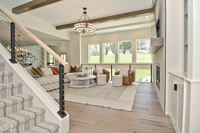 living room with a healthy amount of sunlight, an inviting chandelier, wood finished floors, stairway, and beam ceiling
