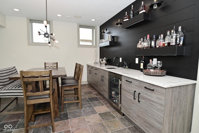 bar with recessed lighting, beverage cooler, stone finish flooring, a sink, and wet bar