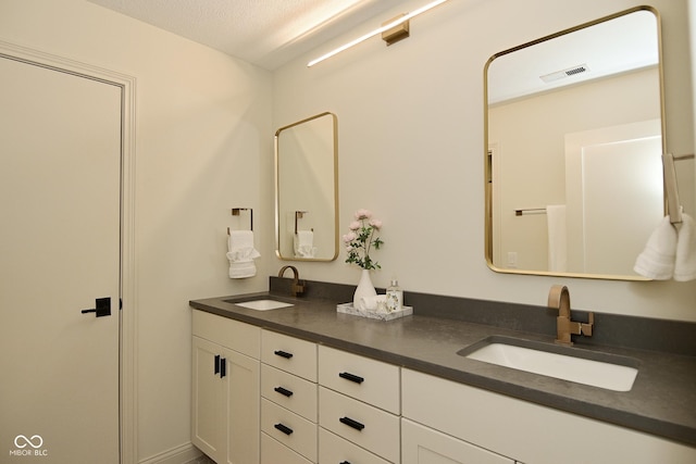 bathroom featuring double vanity, a textured ceiling, and a sink