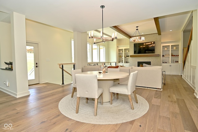 dining space featuring light wood finished floors, an inviting chandelier, and a tiled fireplace