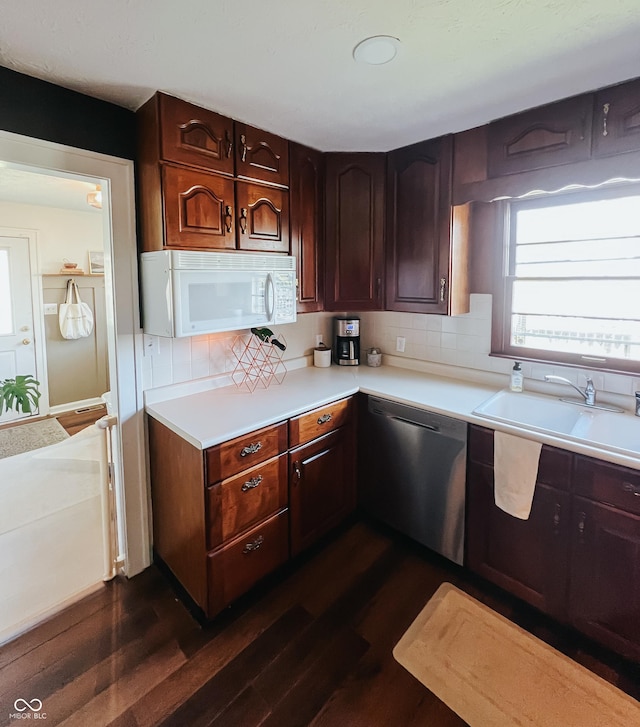 kitchen with stainless steel dishwasher, a sink, dark wood-type flooring, and white microwave