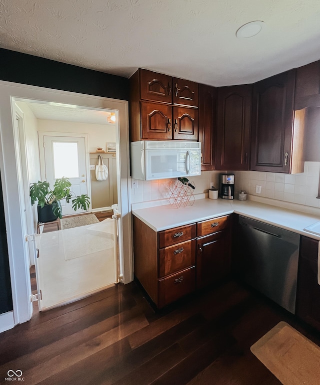 kitchen with white microwave, light countertops, decorative backsplash, dark wood-type flooring, and stainless steel dishwasher