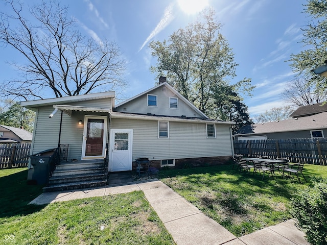 rear view of house featuring fence, a yard, and a chimney