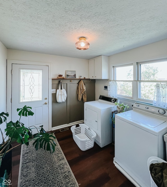 washroom with separate washer and dryer, a textured ceiling, dark wood-style flooring, and cabinet space
