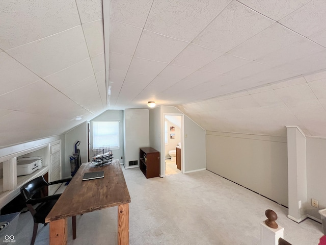 home office featuring light carpet, lofted ceiling, and visible vents