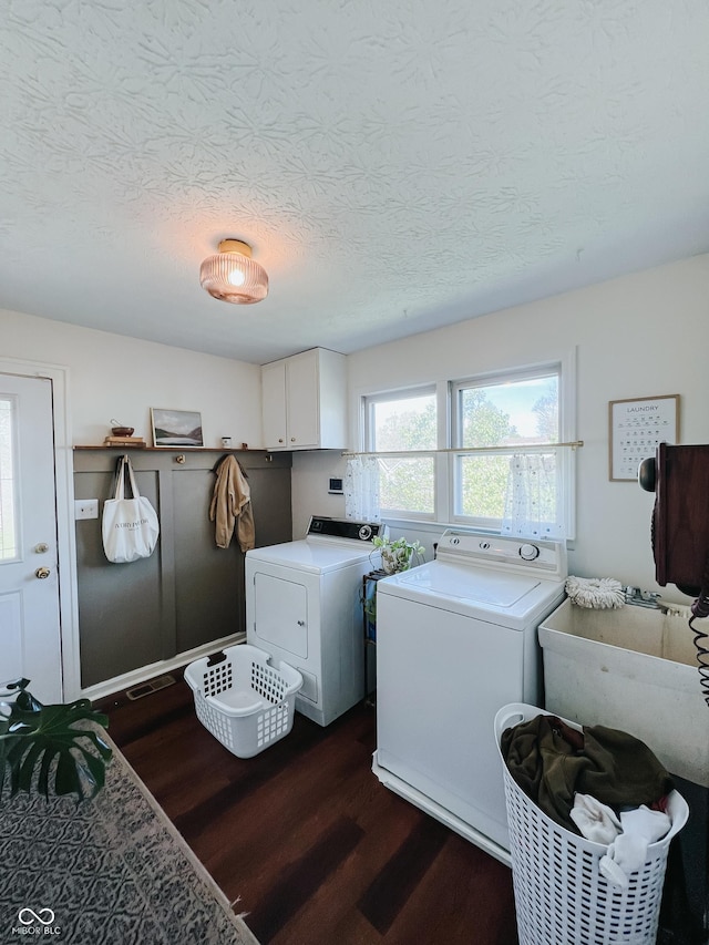 washroom featuring separate washer and dryer, a textured ceiling, dark wood-style flooring, and cabinet space