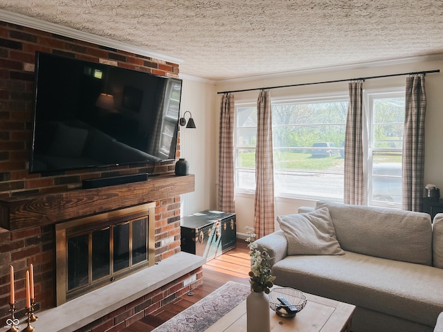 living area featuring a textured ceiling, ornamental molding, a fireplace, and wood finished floors