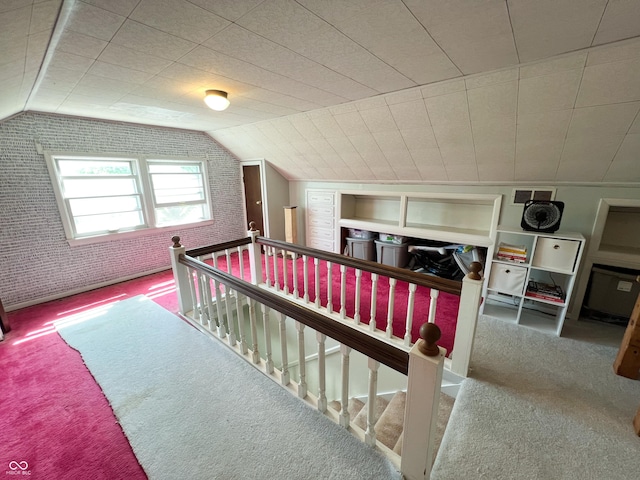 bedroom featuring carpet floors, brick wall, visible vents, and vaulted ceiling