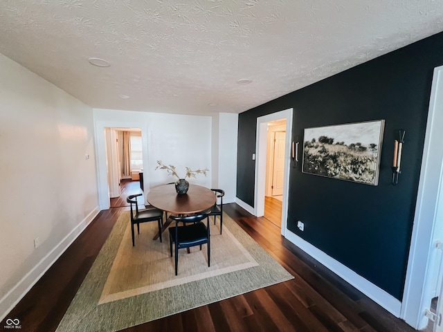 dining space featuring baseboards, a textured ceiling, and wood finished floors