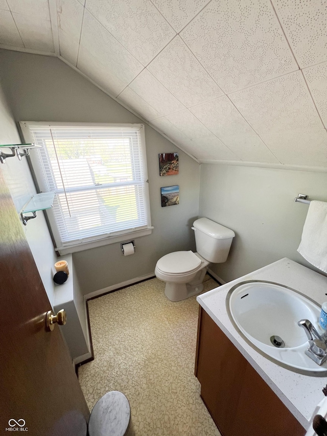 bathroom featuring vanity, baseboards, toilet, and lofted ceiling