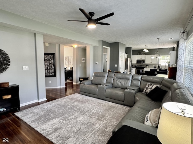 living area featuring baseboards, a textured ceiling, dark wood finished floors, and ceiling fan