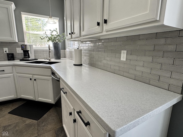 kitchen featuring decorative backsplash, light countertops, white cabinets, a sink, and decorative light fixtures