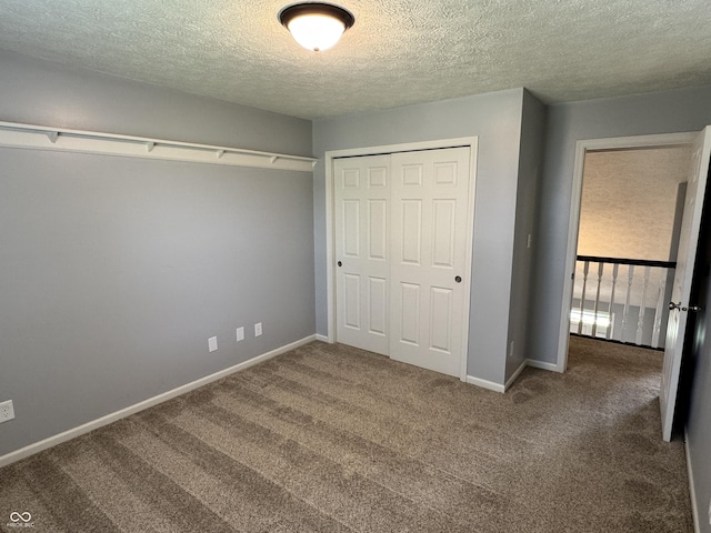 unfurnished bedroom featuring baseboards, a closet, carpet flooring, and a textured ceiling