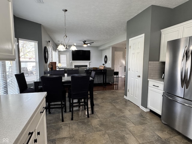 dining area with stone finish floor, a ceiling fan, a textured ceiling, visible vents, and a fireplace