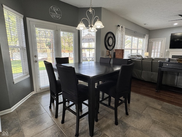 dining space with baseboards, a wealth of natural light, a textured ceiling, and a chandelier