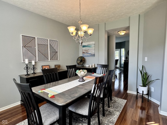 dining room with baseboards, a textured ceiling, dark wood finished floors, and a notable chandelier