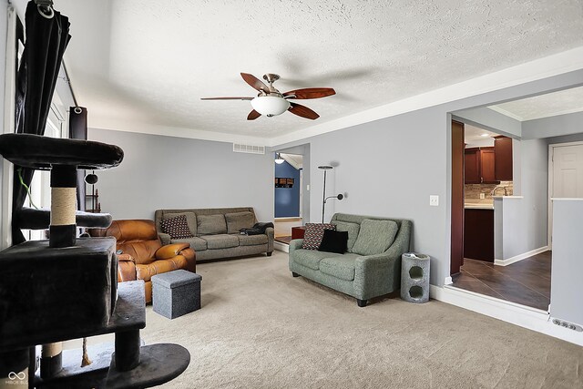 601 Shady Ln, Greenwood, IN 46142 - carpeted living room with visible vents, ornamental molding, baseboards, a textured ceiling, and a ceiling fan