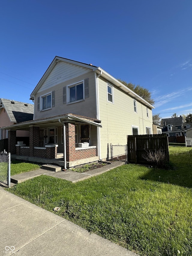 view of front of house with fence, covered porch, a front yard, brick siding, and a gate