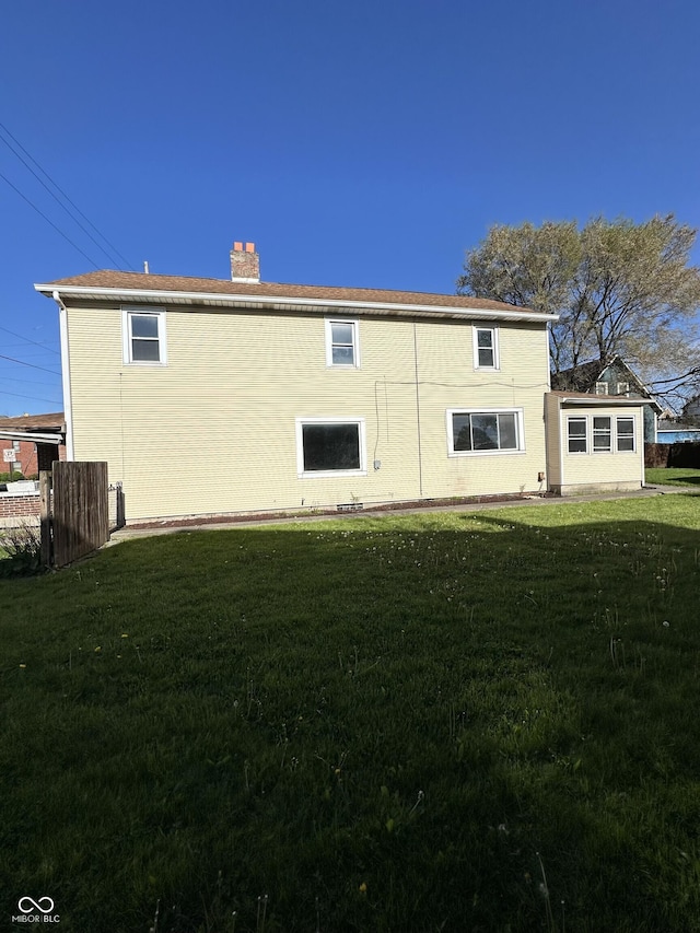 rear view of house featuring a lawn and a chimney