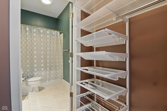 full bathroom featuring toilet, a shower with shower curtain, and baseboards