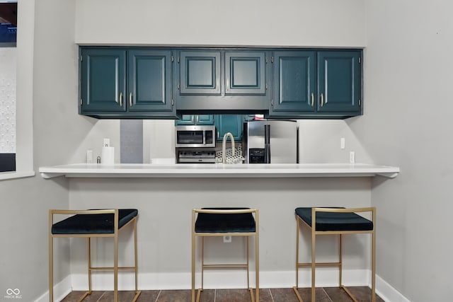 kitchen with appliances with stainless steel finishes, a peninsula, and blue cabinets
