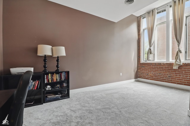 carpeted office with baseboards and brick wall