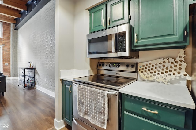 kitchen featuring stainless steel appliances, baseboards, green cabinetry, dark wood-type flooring, and light countertops