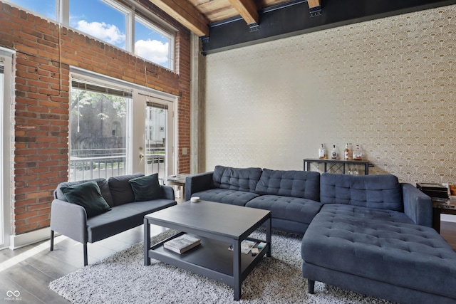 living area with wood finished floors, beam ceiling, and brick wall