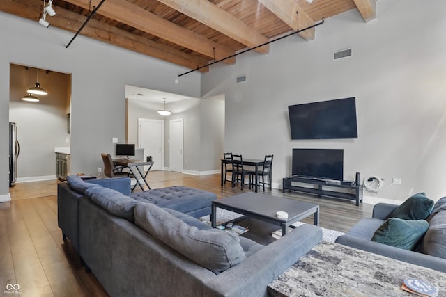 living area with wood ceiling, beamed ceiling, light wood-type flooring, baseboards, and a towering ceiling
