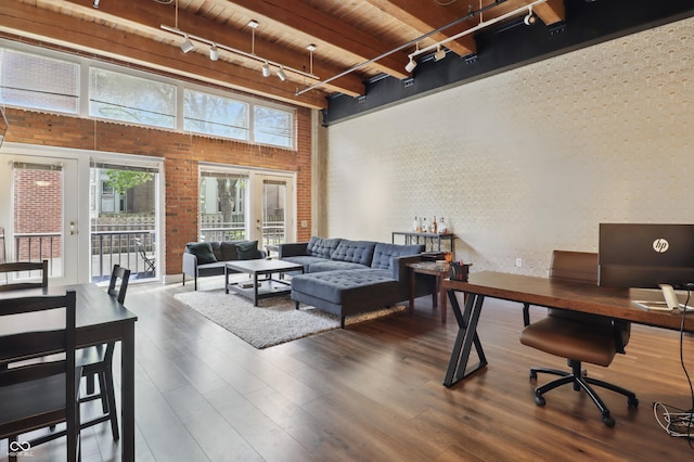 office featuring track lighting, wooden ceiling, brick wall, wood finished floors, and a towering ceiling