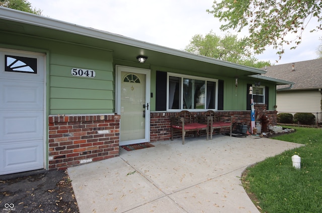 5041 Norcroft Dr, Indianapolis, IN 46221 - entrance to property featuring a garage, a porch, and brick siding